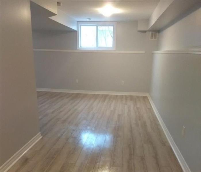 A view of a completely renovated and finished basement, with gleaming hardwood floors and beautifully painted walls and trim