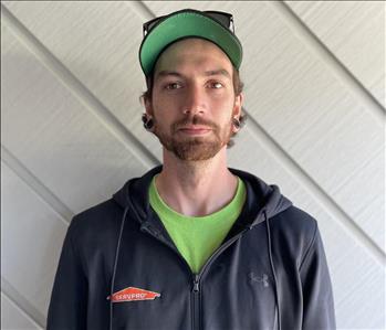 Employee Quinn O'Connor standing infront of a grey wall wearing a black SERVPRO branded sweatshirt.