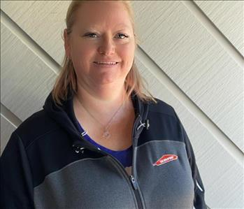 Office Manager Crystal Walsh-Franklin standing infront of a grey wall wearing a grey SERVPRO branded sweatshirt.