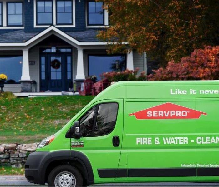 SERVPRO green and orange van parked in front of suburban residence.